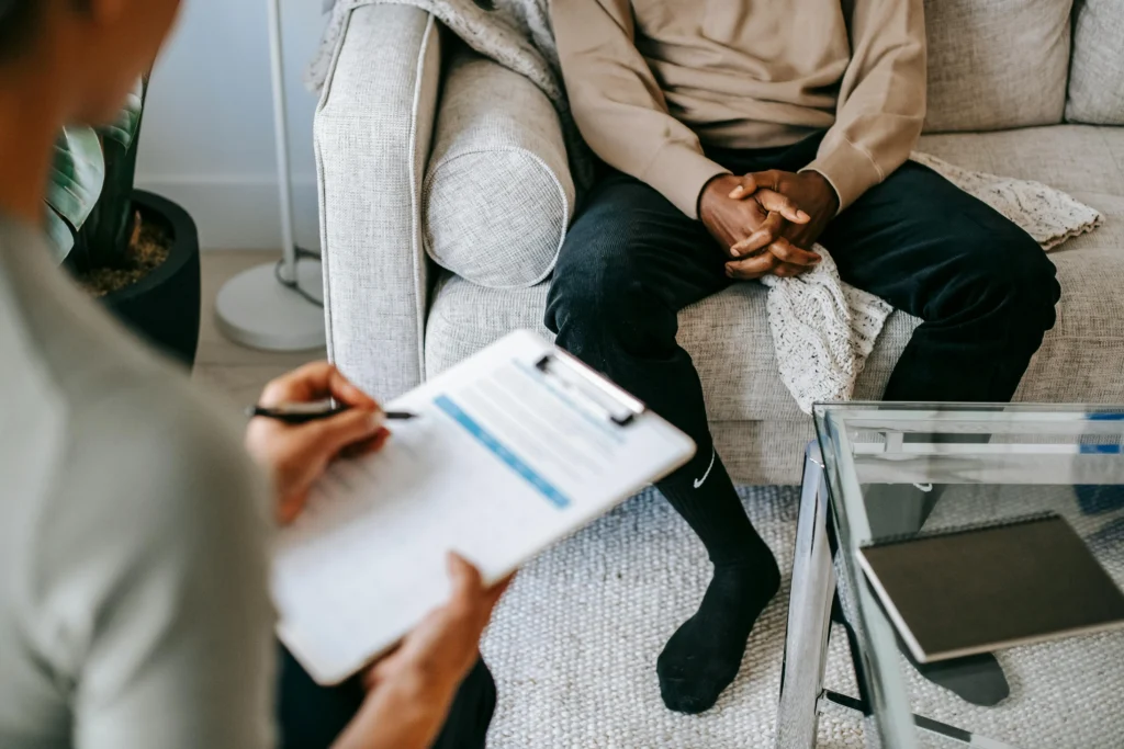 Reunión entre agente inmobiliario de Don Casa y cliente en sofá moderno, revisando documentos y contratos para comprar una propiedad, con mesa de cristal y ambiente profesional en Barcelona.