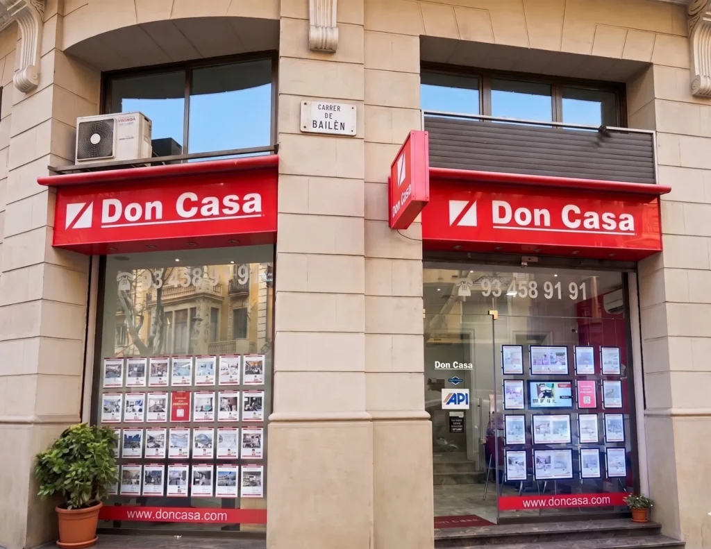 Escaparate de la oficina inmobiliaria Don Casa en el Carrer de Bailèn, mostrando una amplia selección de viviendas en venta y alquiler con el servicio profesional de Inmobiliaria Barcelona.