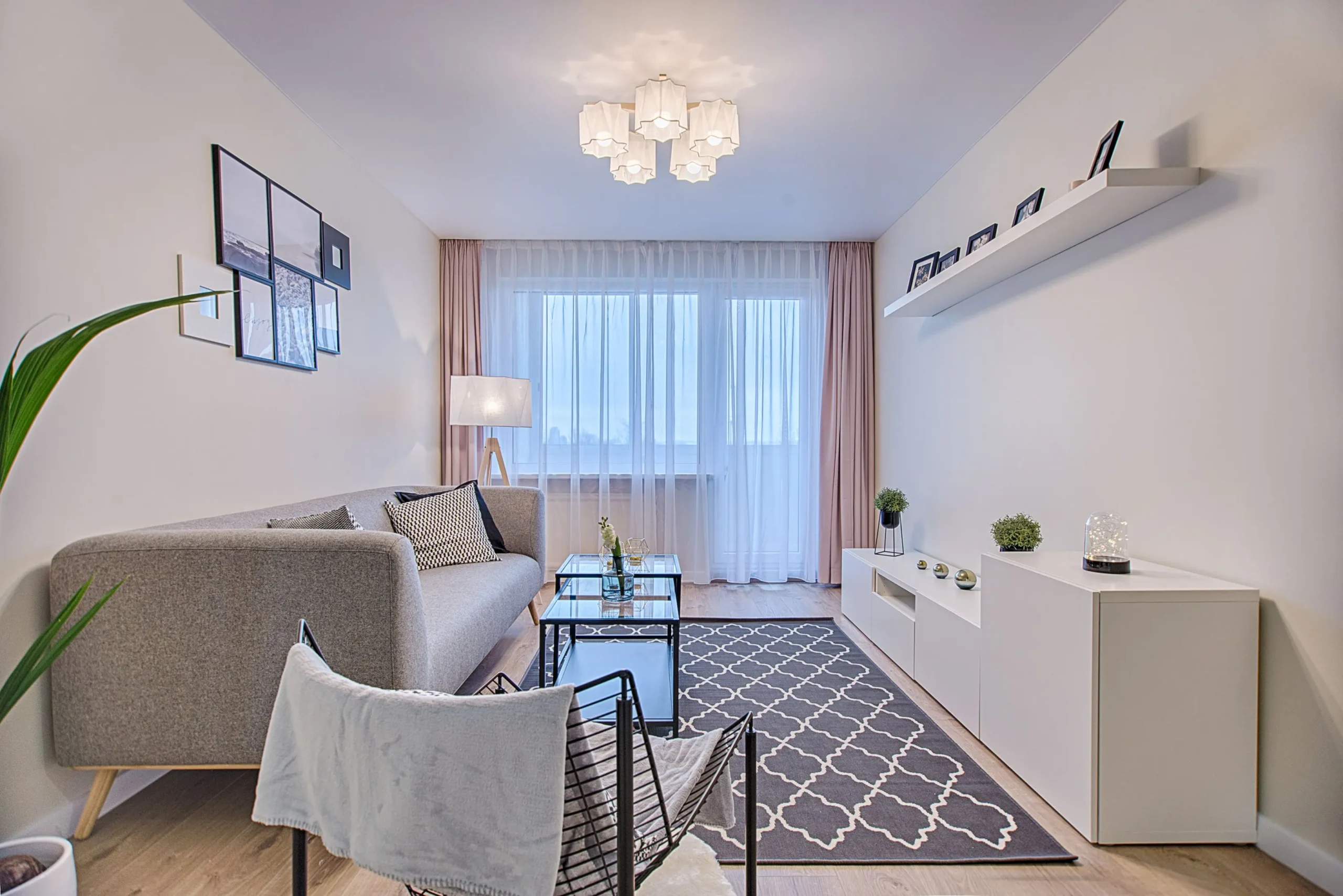 Salón moderno de estilo nórdico con sofá gris, alfombra geométrica, mueble de TV blanco y gran ventanal para vende piso Les Corts con Don Casa Inmobiliaria.