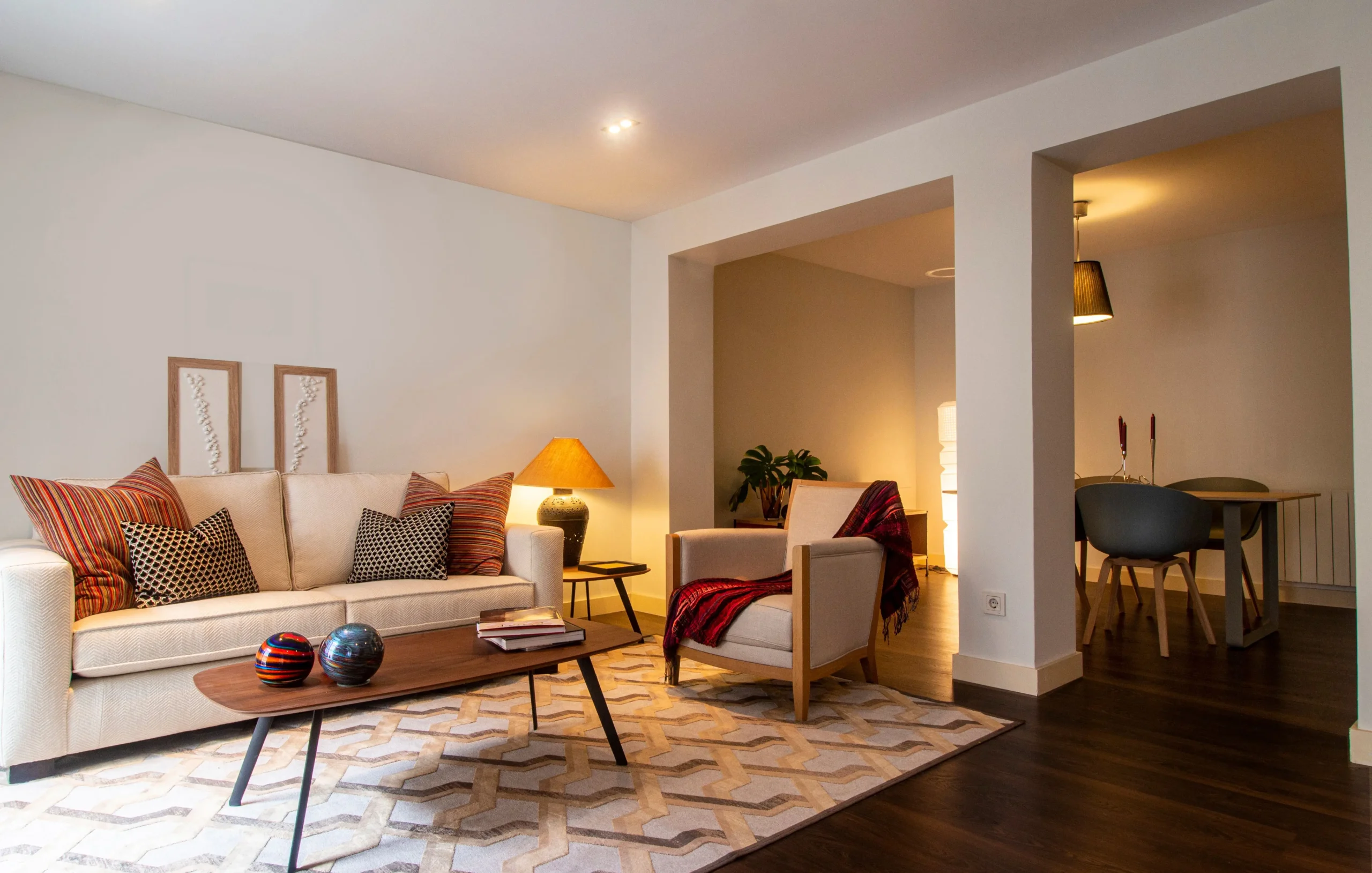 Salón acogedor decorado con sofá beige, alfombra geométrica e iluminación ambiental junto a zona de comedor para vende piso San Martí con Don Casa Inmobiliaria.