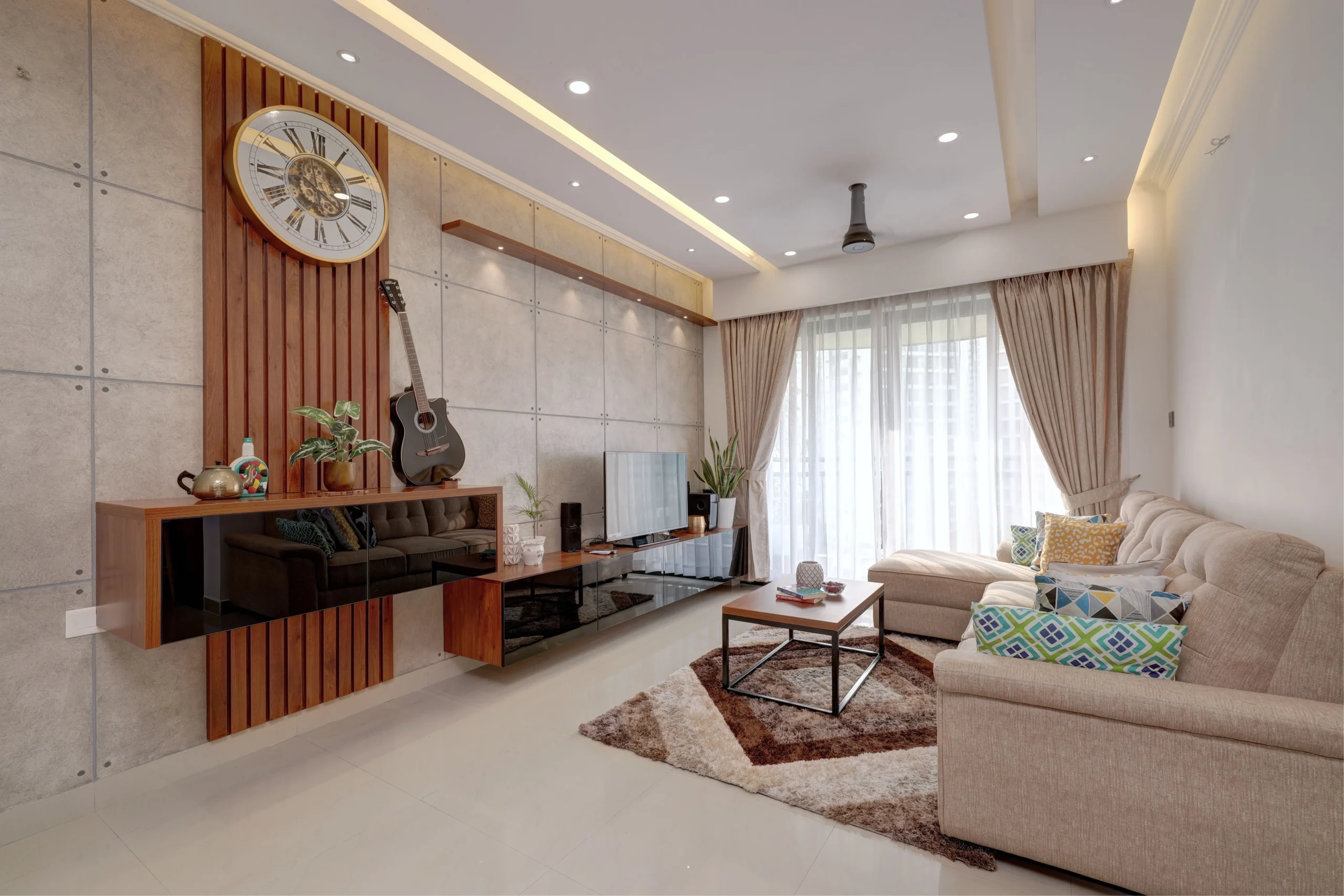Amplio salón de diseño moderno con sofisticada pared de acento de madera y hormigón, sofá chaise longue beige y luz natural para vende piso Gràcia con Don Casa Inmobiliaria.