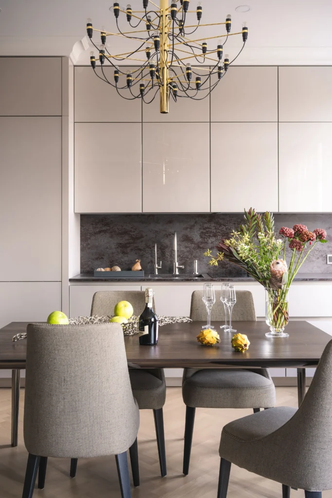 Comedor con mesa de madera, sillas tapizadas y lámpara de araña. En Inmobiliaria en Barcelona